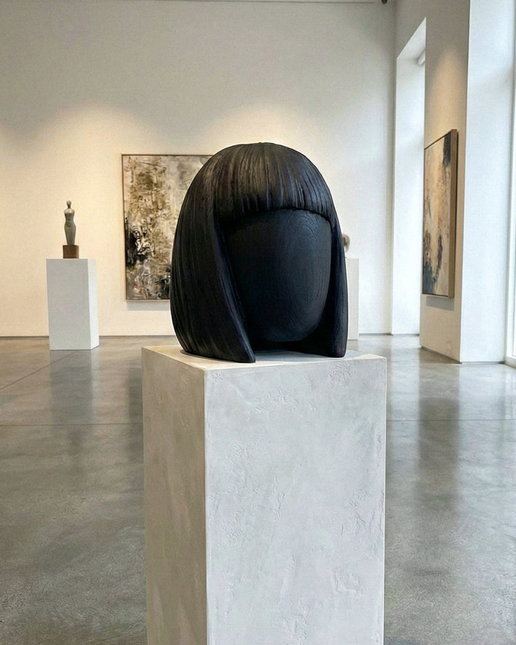 Black abstract sculpture on a pedestal in an art gallery setting