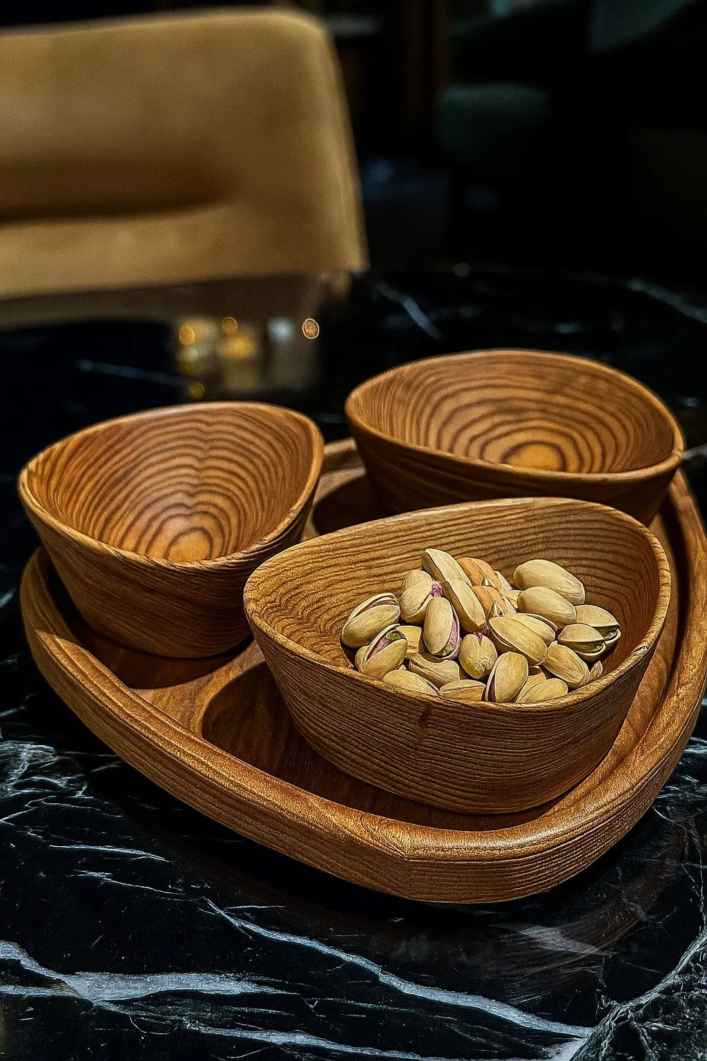 Wooden bowls with pistachios on a dark surface