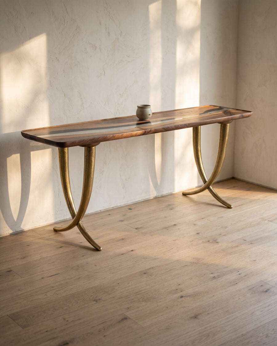 Walnut and resin console table with brass legs against a plaster wall