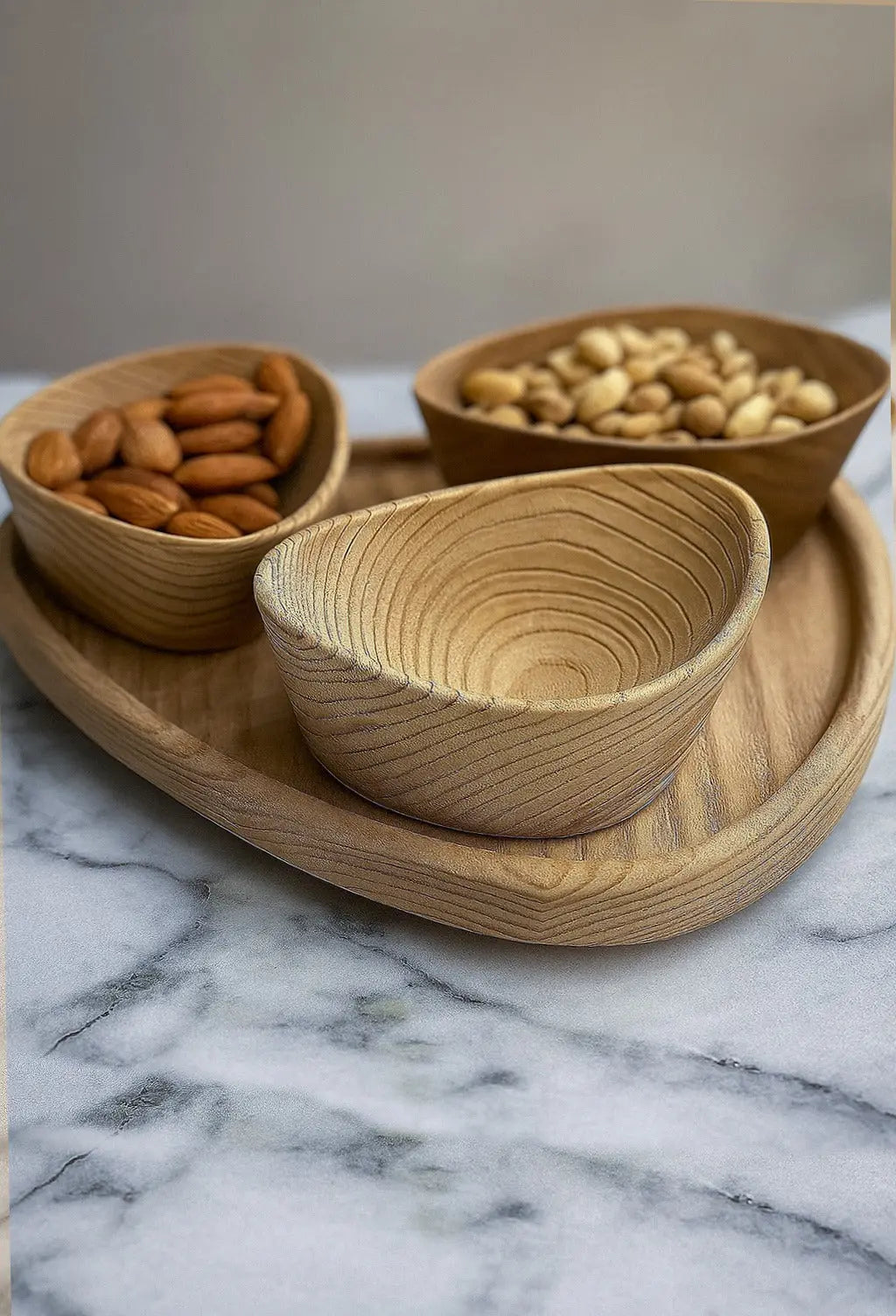 Set of wooden bowls with nuts on a marble surface