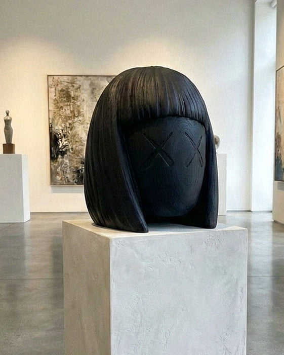 Sculpture on a pedestal in an art gallery with other artworks and white walls.