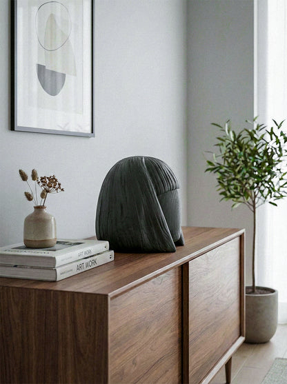 Modern interior with a wooden sideboard, decorative vase, books, and abstract art on a light gray wall.