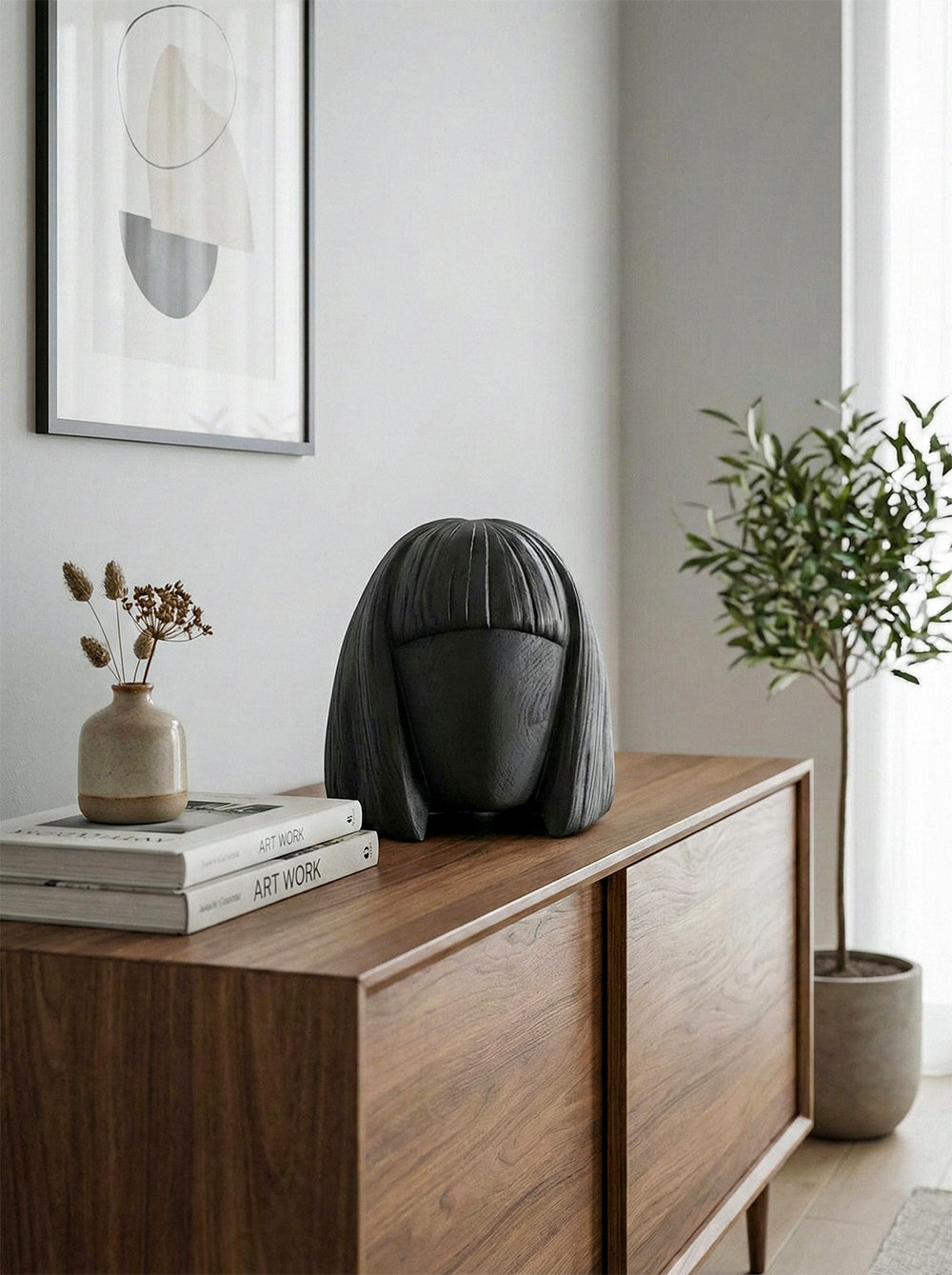 Black speaker on a wooden sideboard with decor items in a room.