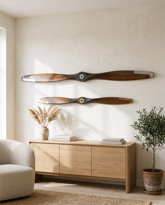 Two wooden airplane propellers, 180 cm with silver hub and 120 cm with brass hub, mounted on a bright living room wall
