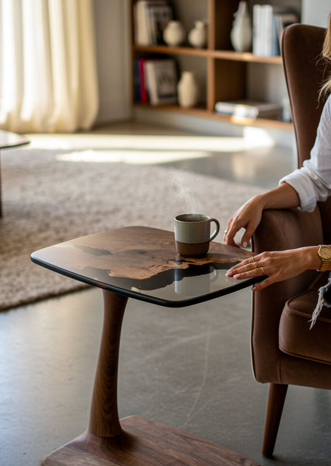 Person sitting in a chair with a wooden side table and mug in a cozy room.
