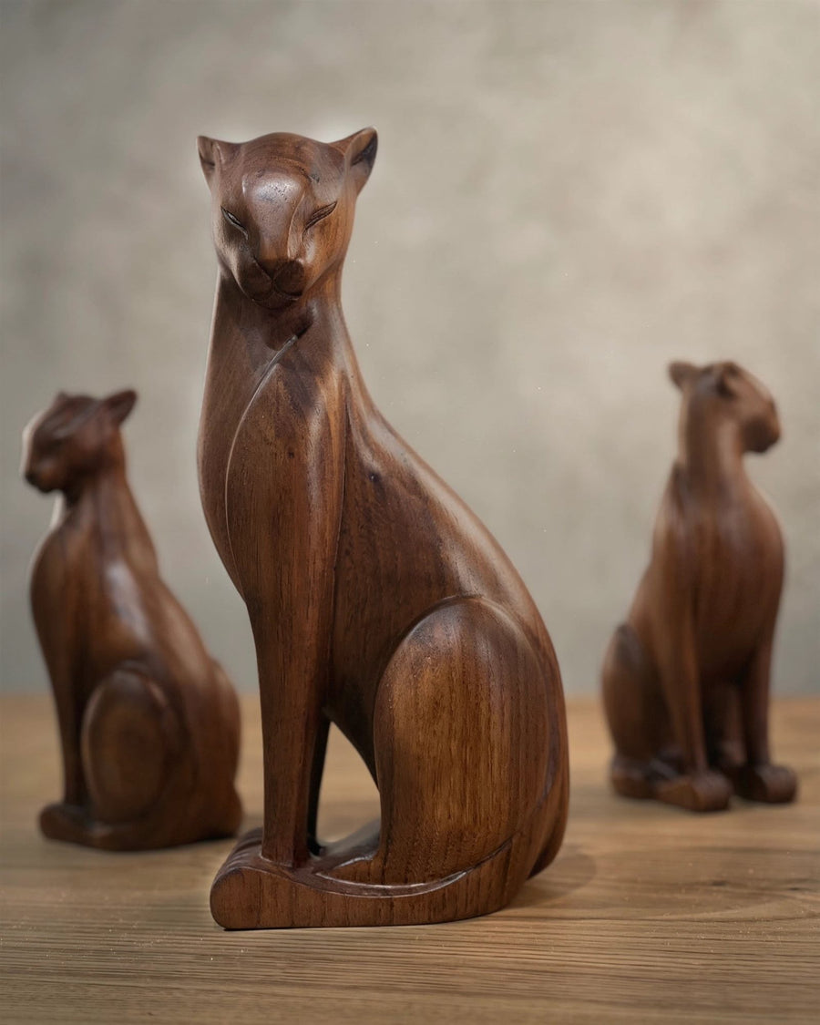 Carved walnut cat sculptures on a wooden surface